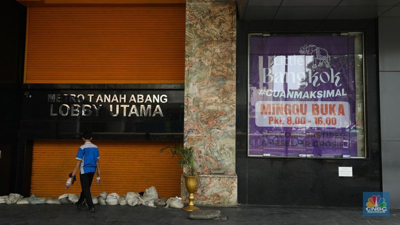 Warga melintas di depan Pasar Tanah Abang Blok A yang tutup di Jakarta, Selasa (16/4/2024). (CNBC Indonesia/Tri Susilo)