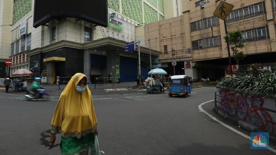 Warga melintas di depan Pasar Tanah Abang Blok A yang tutup di Jakarta, Selasa (16/4/2024). (CNBC Indonesia/Tri Susilo)