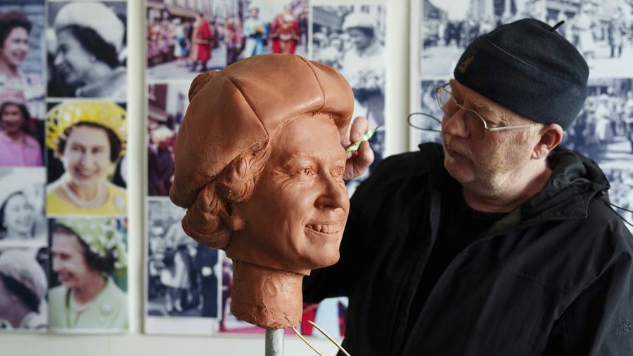 Pematung Staffordshire Andy Edwards berpose sambil menyempurnakan studi potret dengan lilin untuk patung Ratu Elizabeth II yang ditugaskan oleh Dewan Borough Newcastle-under-Lyme untuk menandai ulang tahun ke-850 wilayah tersebut, Newcastle-Under-Lyme, Inggris, Kamis, 18 April 2024. Edwards yang karya sebelumnya termasuk patung terkenal Beatles di Pier Head Liverpool, mendasarkan patung tersebut pada foto kunjungan mendiang Ratu ke Newcastle-under-Lyme sebagai bagian dari perayaan ulang tahun ke-800 Borough pada tahun 1973. (AP Photo/Jon Super)