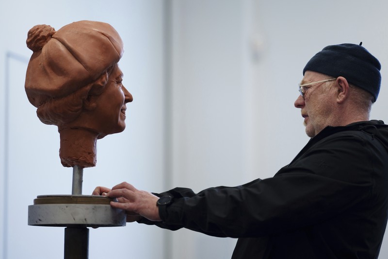 Pematung Staffordshire Andy Edwards berpose sambil menyempurnakan studi potret dengan lilin untuk patung Ratu Elizabeth II yang ditugaskan oleh Dewan Borough Newcastle-under-Lyme untuk menandai ulang tahun ke-850 wilayah tersebut, Newcastle-Under-Lyme, Inggris, Kamis, 18 April 2024. Edwards yang karya sebelumnya termasuk patung terkenal Beatles di Pier Head Liverpool, mendasarkan patung tersebut pada foto kunjungan mendiang Ratu ke Newcastle-under-Lyme sebagai bagian dari perayaan ulang tahun ke-800 Borough pada tahun 1973. (AP Photo/Jon Super)