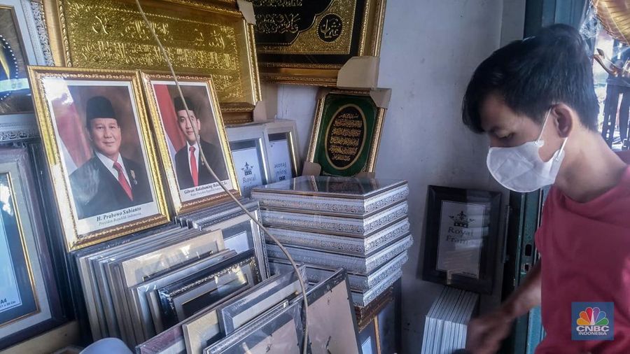Seorang pedagang menata bingkai foto calon Presiden dan Wakil Presiden terpilih Prabowo Subianto dan Gibran Rakabuming Raka di Kawasan Jalan Jatinegara Jatim, Sabtu (20/4/2024). (վ/Suhendra)