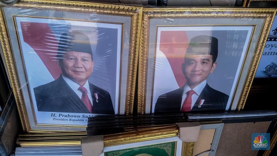 Seorang pedagang menata bingkai foto calon Presiden dan Wakil Presiden terpilih Prabowo Subianto dan Gibran Rakabuming Raka di Kawasan Jalan Jatinegara Jatim, Sabtu (20/4/2024). (CNBC Indonesia/Suhendra)