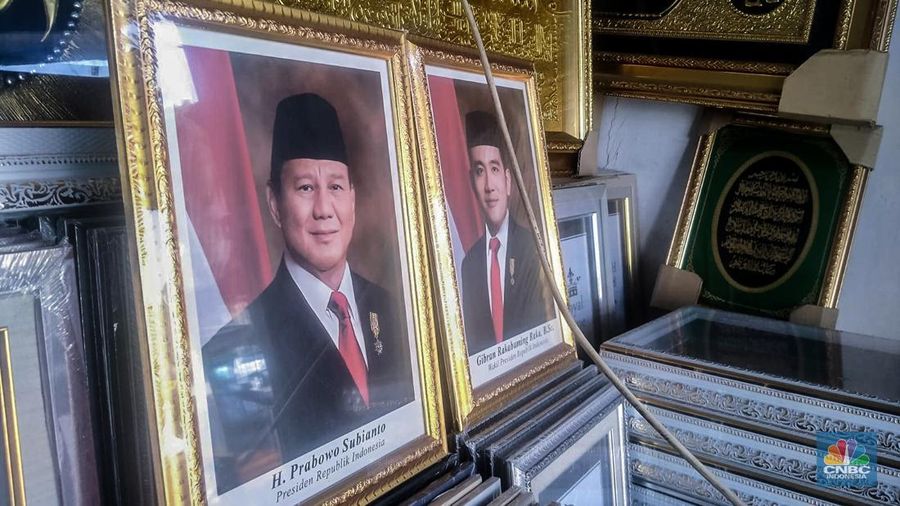 Seorang pedagang menata bingkai foto calon Presiden dan Wakil Presiden terpilih Prabowo Subianto dan Gibran Rakabuming Raka di Kawasan Jalan Jatinegara Jatim, Sabtu (20/4/2024). (CNBC Indonesia/Suhendra)