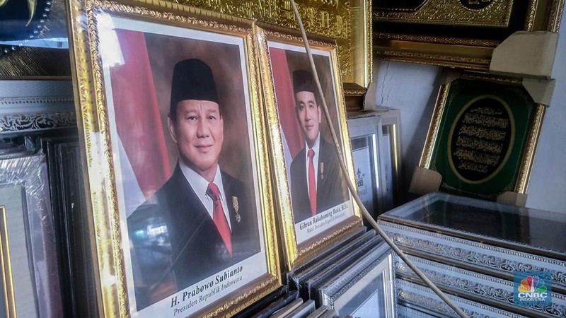 Seorang pedagang menata bingkai foto calon Presiden dan Wakil Presiden terpilih Prabowo Subianto dan Gibran Rakabuming Raka di Kawasan Jalan Jatinegara Jatim, Sabtu (20/4/2024). (CNBC Indonesia/Suhendra)