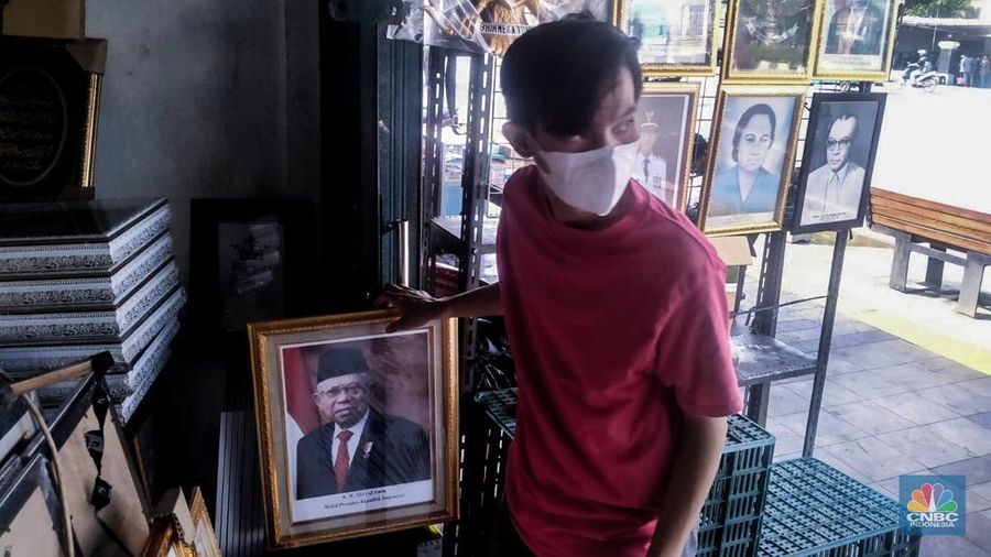 Seorang pedagang menata bingkai foto calon Presiden dan Wakil Presiden terpilih Prabowo Subianto dan Gibran Rakabuming Raka di Kawasan Jalan Jatinegara Jatim, Sabtu (20/4/2024). (CNBC Indonesia/Suhendra)