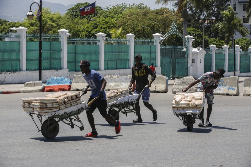 Seorang pria mengangkat rantai yang digunakan sebagai barikade agar tetangga dapat masuk ke lingkungan tersebut saat mereka bekerja menyiapkan gerbang logam untuk melindungi diri dari geng, di lingkungan Petion-Ville di Port-au-Prince, Haiti, Sabtu, 20 April , 2024. (AP Photo/Ramon Espinosa)