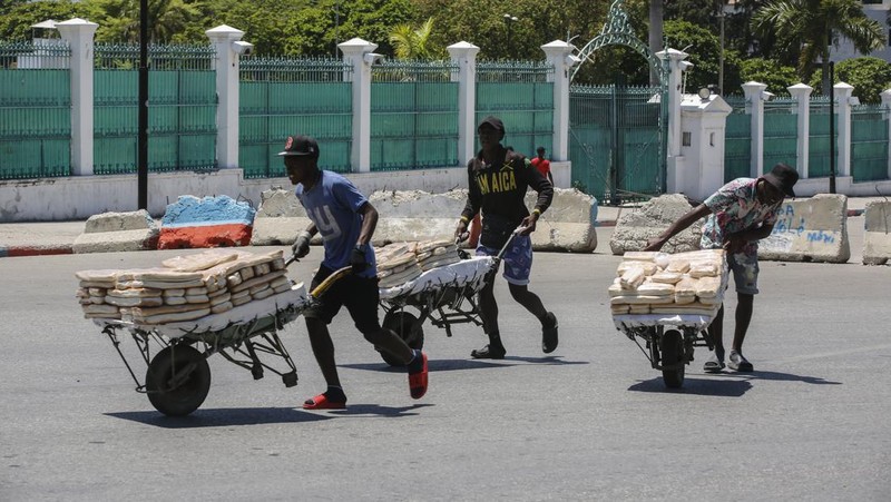 Seorang pria mengangkat rantai yang digunakan sebagai barikade agar tetangga dapat masuk ke lingkungan tersebut saat mereka bekerja menyiapkan gerbang logam untuk melindungi diri dari geng, di lingkungan Petion-Ville di Port-au-Prince, Haiti, Sabtu, 20 April , 2024. (AP Photo/Ramon Espinosa)