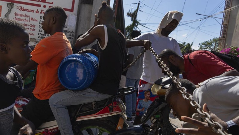 Seorang pria mengangkat rantai yang digunakan sebagai barikade agar tetangga dapat masuk ke lingkungan tersebut saat mereka bekerja menyiapkan gerbang logam untuk melindungi diri dari geng, di lingkungan Petion-Ville di Port-au-Prince, Haiti, Sabtu, 20 April , 2024. (AP Photo/Ramon Espinosa)