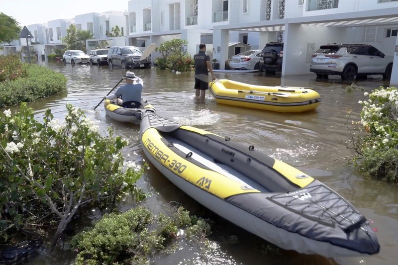 Residents canoe through the Mudon neighborhood in Dubai, United Arab Emirates, Thursday, April 18, 2024. The United Arab Emirates attempted to dry out Thursday from the heaviest rain the desert nation has ever recorded — a deluge that flooded out Dubai International Airport and disrupted flights through the world's busiest airfield for international travel. (AP Photo/Jon Gambrell)