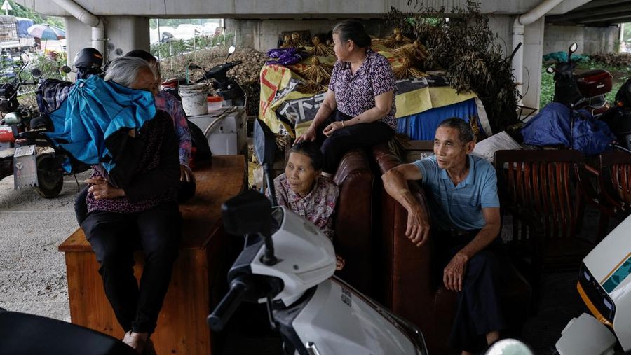 Warga dari daerah yang terkena dampak banjir duduk di jalan bawah tanah dengan perabotan yang dipindahkan dari rumah mereka, menyusul hujan lebat di sebuah desa, di Qingyuan, provinsi Guangdong, Tiongkok 22 April 2024. (REUTERS/Tingshu Wang)