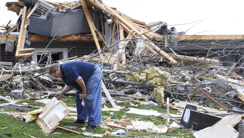 Penghuni rumah membersihkan puing-puing bangunan yang rusak pasca tornado di Omaha, Nebraska, AS, 26 April 2024. (Nikos Frazier/Omaha World-Herald via AP)
