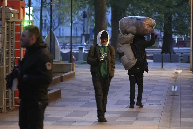 Seorang migran mengemas barang-barangnya di kamp darurat, Selasa dini hari, 23 April 2024 di Paris. Petugas polisi Prancis telah mengusir para migran dari kamp darurat di Paris yang berjarak beberapa langkah dari Sungai Seine, karena operasi serupa telah dilakukan oleh pihak berwenang menjelang Olimpiade. (AP Photo/Nicolas Garriga)