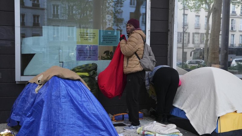 Seorang migran mengemas barang-barangnya di kamp darurat, Selasa dini hari, 23 April 2024 di Paris. Petugas polisi Prancis telah mengusir para migran dari kamp darurat di Paris yang berjarak beberapa langkah dari Sungai Seine, karena operasi serupa telah dilakukan oleh pihak berwenang menjelang Olimpiade. (AP Photo/Nicolas Garriga)