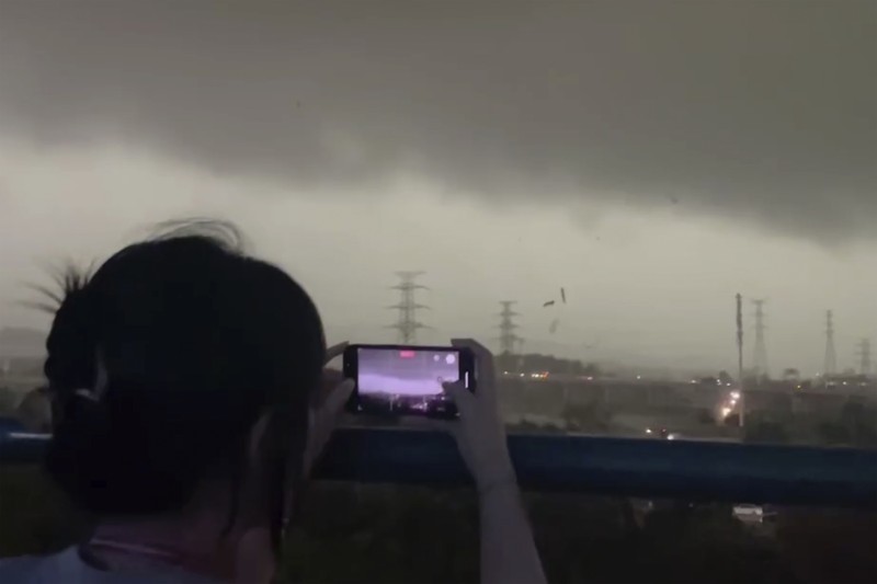 Seorang warga mendokumentasikan detik-detik bencana alam angin tornado melanda Guangzhou, ibu kota provinsi Guangdong, Sabtu 27 April 2024, terekam kamera. (AP/Li Jiayi)