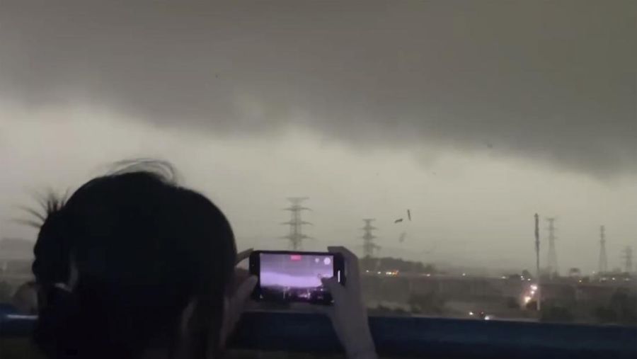 Seorang warga mendokumentasikan detik-detik bencana alam angin tornado melanda Guangzhou, ibu kota provinsi Guangdong, Sabtu 27 April 2024, terekam kamera. (AP/Li Jiayi)
