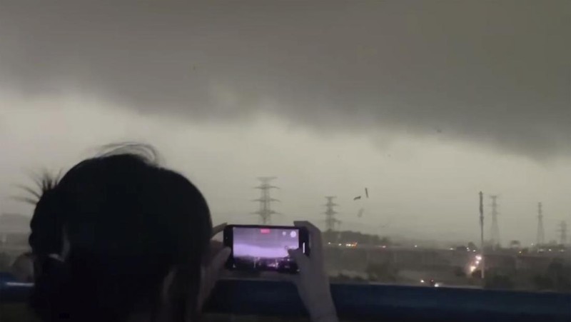 Seorang warga mendokumentasikan detik-detik bencana alam angin tornado melanda Guangzhou, ibu kota provinsi Guangdong, Sabtu 27 April 2024, terekam kamera. (AP/Li Jiayi)
