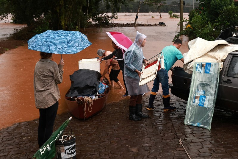 Orang-orang menyelamatkan barang-barang mereka di daerah banjir di sebelah Sungai Taquari saat hujan lebat di kota Encantado di Rio Grande do Sul, Brasil, 1 Mei 2024. (REUTERS/Diego Vara)