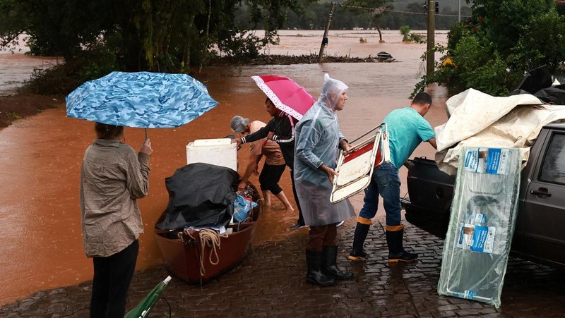Orang-orang menyelamatkan barang-barang mereka di daerah banjir di sebelah Sungai Taquari saat hujan lebat di kota Encantado di Rio Grande do Sul, Brasil, 1 Mei 2024. (REUTERS/Diego Vara)