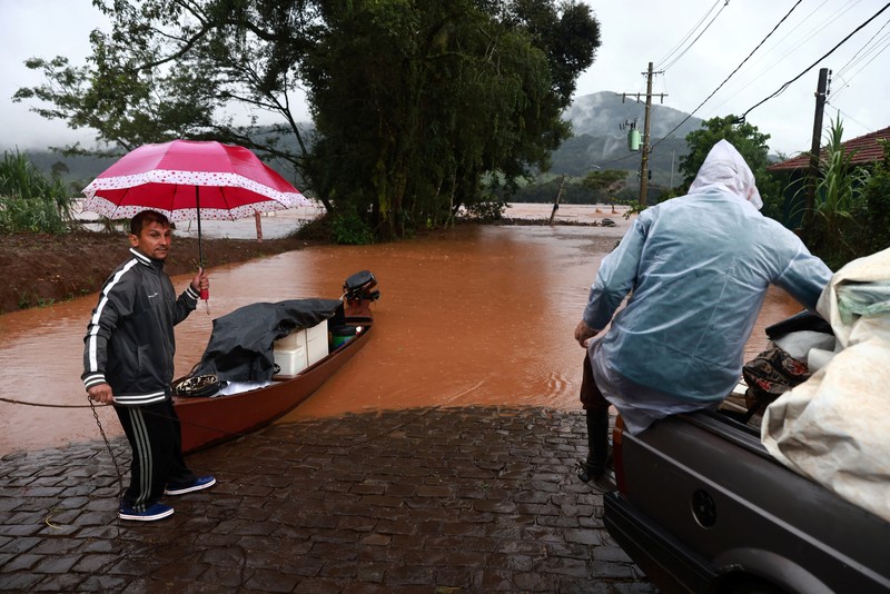 Orang-orang menyelamatkan barang-barang mereka di daerah banjir di sebelah Sungai Taquari saat hujan lebat di kota Encantado di Rio Grande do Sul, Brasil, 1 Mei 2024. (REUTERS/Diego Vara)