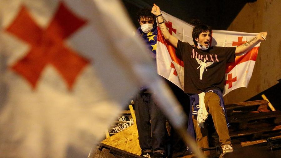 Seorang pengunjuk rasa membawa bendera Georgia saat unjuk rasa memprotes RUU tentang