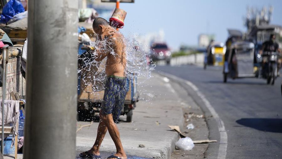 Seorang pria mendinginkan badan di sepanjang jalan untuk meredakan suhu panas di Manila, Filipina pada Jumat, 26 April 2024. (AP Photo/Aaron Favila)