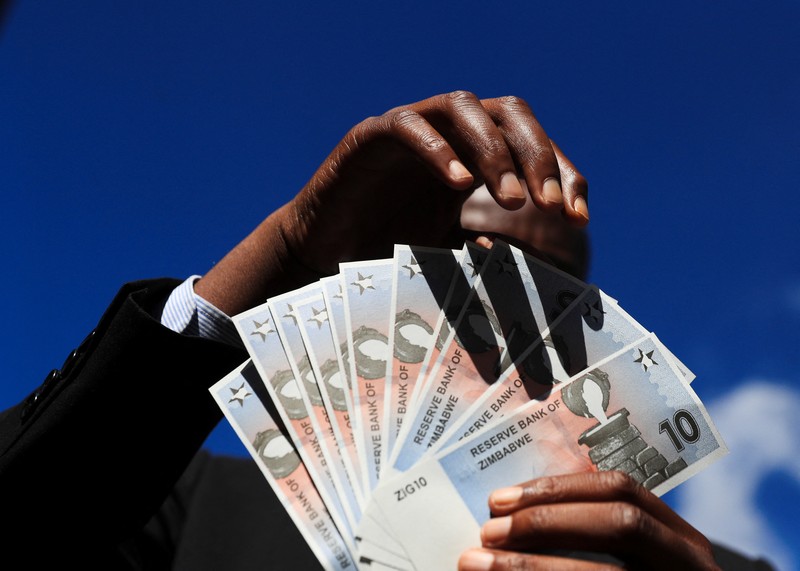 Seorang wanita memegang uang kertas dan koin Zimbabwe baru yang disebut ZiG, di jalan-jalan Harare, Zimbabwe, Selasa, 30 April 2024. Seorang wanita memegang uang kertas dan koin Zimbabwe baru yang disebut ZiG, di jalan-jalan Harare, Zimbabwe, Selasa, 30 April 2024. Zimbabwe mulai mengedarkan uang kertas dan koin untuk mata uang baru lainnya pada hari Selasa dalam upaya terbarunya untuk menyelesaikan permasalahan jangka panjang dan terkadang krisis moneter membingungkan yang membuat pemerintah mencoba koin emas dan mata uang digital di antara ide-ide lainnya. (AP Photo/Tsvangirayi Mukwazhi)