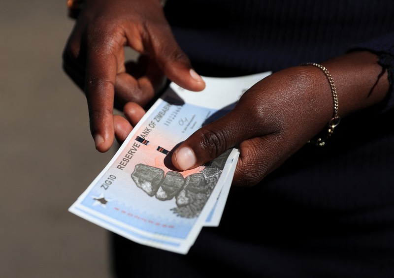 Seorang wanita memegang uang kertas dan koin Zimbabwe baru yang disebut ZiG, di jalan-jalan Harare, Zimbabwe, Selasa, 30 April 2024. Seorang wanita memegang uang kertas dan koin Zimbabwe baru yang disebut ZiG, di jalan-jalan Harare, Zimbabwe, Selasa, 30 April 2024. Zimbabwe mulai mengedarkan uang kertas dan koin untuk mata uang baru lainnya pada hari Selasa dalam upaya terbarunya untuk menyelesaikan permasalahan jangka panjang dan terkadang krisis moneter membingungkan yang membuat pemerintah mencoba koin emas dan mata uang digital di antara ide-ide lainnya. (AP Photo/Tsvangirayi Mukwazhi)