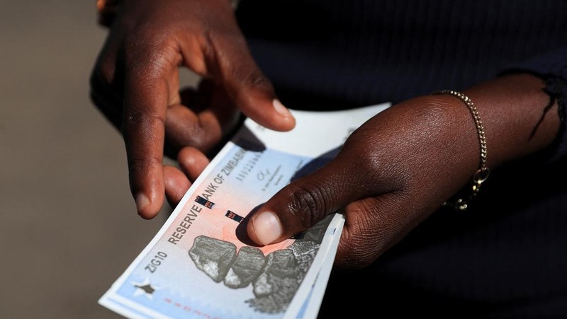 Seorang wanita memegang uang kertas dan koin Zimbabwe baru yang disebut ZiG, di jalan-jalan Harare, Zimbabwe, Selasa, 30 April 2024. Zimbabwe mulai mengedarkan uang kertas dan koin untuk mata uang baru lainnya pada hari Selasa dalam upaya terbarunya untuk menyelesaikan permasalahan jangka panjang dan terkadang krisis moneter membingungkan yang membuat pemerintah mencoba koin emas dan mata uang digital di antara ide-ide lainnya. (AP Photo/Tsvangirayi Mukwazhi)