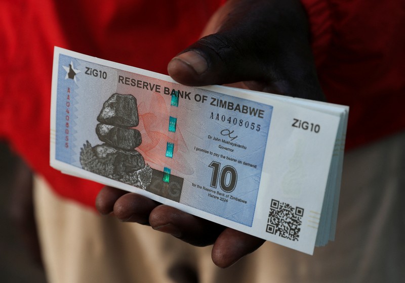 Seorang wanita memegang uang kertas dan koin Zimbabwe baru yang disebut ZiG, di jalan-jalan Harare, Zimbabwe, Selasa, 30 April 2024. Seorang wanita memegang uang kertas dan koin Zimbabwe baru yang disebut ZiG, di jalan-jalan Harare, Zimbabwe, Selasa, 30 April 2024. Zimbabwe mulai mengedarkan uang kertas dan koin untuk mata uang baru lainnya pada hari Selasa dalam upaya terbarunya untuk menyelesaikan permasalahan jangka panjang dan terkadang krisis moneter membingungkan yang membuat pemerintah mencoba koin emas dan mata uang digital di antara ide-ide lainnya. (AP Photo/Tsvangirayi Mukwazhi)