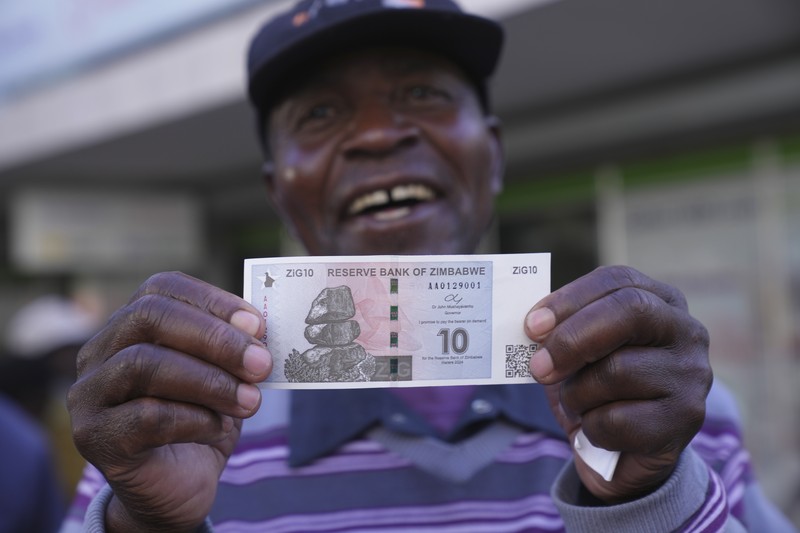 Seorang wanita memegang uang kertas dan koin Zimbabwe baru yang disebut ZiG, di jalan-jalan Harare, Zimbabwe, Selasa, 30 April 2024. Seorang wanita memegang uang kertas dan koin Zimbabwe baru yang disebut ZiG, di jalan-jalan Harare, Zimbabwe, Selasa, 30 April 2024. Zimbabwe mulai mengedarkan uang kertas dan koin untuk mata uang baru lainnya pada hari Selasa dalam upaya terbarunya untuk menyelesaikan permasalahan jangka panjang dan terkadang krisis moneter membingungkan yang membuat pemerintah mencoba koin emas dan mata uang digital di antara ide-ide lainnya. (AP Photo/Tsvangirayi Mukwazhi)