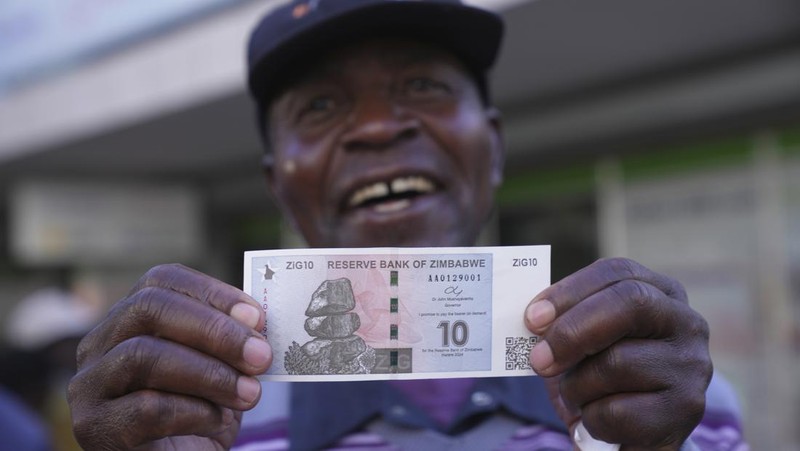 Seorang wanita memegang uang kertas dan koin Zimbabwe baru yang disebut ZiG, di jalan-jalan Harare, Zimbabwe, Selasa, 30 April 2024. Zimbabwe mulai mengedarkan uang kertas dan koin untuk mata uang baru lainnya pada hari Selasa dalam upaya terbarunya untuk menyelesaikan permasalahan jangka panjang dan terkadang krisis moneter membingungkan yang membuat pemerintah mencoba koin emas dan mata uang digital di antara ide-ide lainnya. (AP Photo/Tsvangirayi Mukwazhi)