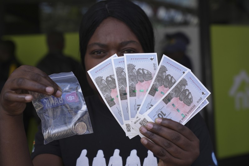 Seorang wanita memegang uang kertas dan koin Zimbabwe baru yang disebut ZiG, di jalan-jalan Harare, Zimbabwe, Selasa, 30 April 2024. Seorang wanita memegang uang kertas dan koin Zimbabwe baru yang disebut ZiG, di jalan-jalan Harare, Zimbabwe, Selasa, 30 April 2024. Zimbabwe mulai mengedarkan uang kertas dan koin untuk mata uang baru lainnya pada hari Selasa dalam upaya terbarunya untuk menyelesaikan permasalahan jangka panjang dan terkadang krisis moneter membingungkan yang membuat pemerintah mencoba koin emas dan mata uang digital di antara ide-ide lainnya. (AP Photo/Tsvangirayi Mukwazhi)