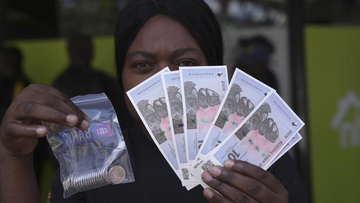 Seorang wanita memegang uang kertas dan koin Zimbabwe baru yang disebut ZiG, di jalan-jalan Harare, Zimbabwe, Selasa, 30 April 2024. Zimbabwe mulai mengedarkan uang kertas dan koin untuk mata uang baru lainnya pada hari Selasa dalam upaya terbarunya untuk menyelesaikan permasalahan jangka panjang dan terkadang krisis moneter membingungkan yang membuat pemerintah mencoba koin emas dan mata uang digital di antara ide-ide lainnya. (AP Photo/Tsvangirayi Mukwazhi)