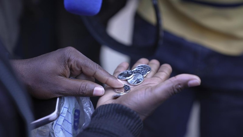 Seorang wanita memegang uang kertas dan koin Zimbabwe baru yang disebut ZiG, di jalan-jalan Harare, Zimbabwe, Selasa, 30 April 2024. Zimbabwe mulai mengedarkan uang kertas dan koin untuk mata uang baru lainnya pada hari Selasa dalam upaya terbarunya untuk menyelesaikan permasalahan jangka panjang dan terkadang krisis moneter membingungkan yang membuat pemerintah mencoba koin emas dan mata uang digital di antara ide-ide lainnya. (AP Photo/Tsvangirayi Mukwazhi)