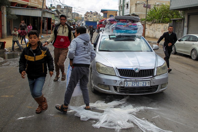 Orang-orang bergegas mengambil kantong tepung dari truk setelah militer Israel mulai mengevakuasi warga sipil Palestina menjelang ancaman serangan di Rafah, di tengah konflik yang sedang berlangsung antara Israel dan Hamas, di Rafah, di selatan Jalur Gaza 6 Mei 2024. Orang-orang bergegas mengambil kantong tepung dari truk setelah militer Israel mulai mengevakuasi warga sipil Palestina menjelang ancaman serangan di Rafah, di tengah konflik yang sedang berlangsung antara Israel dan Hamas, di Rafah, di selatan Jalur Gaza 6 Mei 2024. (REUTERS/Hatem Khaled)