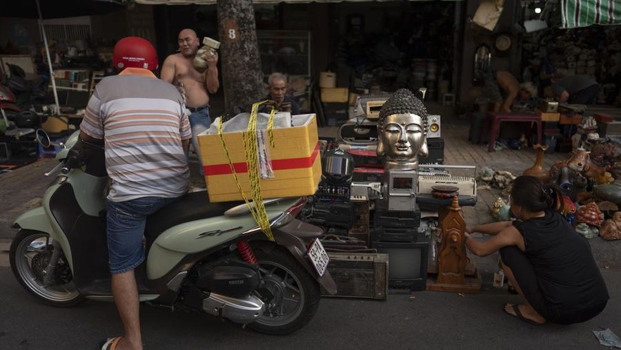 Patung kepala Buddha diletakkan di atas perangkat elektronik bekas saat pembeli mencari barang di Pasar Nhat Tao, pasar daur ulang informal terbesar di Kota Ho Chi Minh, Vietnam, pada Rabu, 31 Januari 2024. (AP Photo/Jae C. Hong)