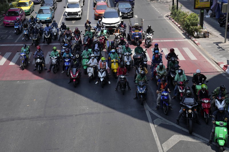 Orang-orang berjalan dengan payung melewati percikan air ketika pihak berwenang Thailand mengatakan bahwa orang-orang meninggal karena serangan panas tahun ini dan memperingatkan untuk menghindari aktivitas di luar ruangan, di Bangkok, Thailand, 5 Mei 2024. (REUTERS/Chalinee Thirasupa)