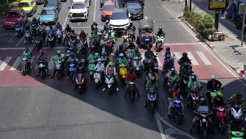 Orang-orang berjalan dengan payung melewati percikan air ketika pihak berwenang Thailand mengatakan bahwa orang-orang meninggal karena serangan panas tahun ini dan memperingatkan untuk menghindari aktivitas di luar ruangan, di Bangkok, Thailand, 5 Mei 2024. (REUTERS/Chalinee Thirasupa)
