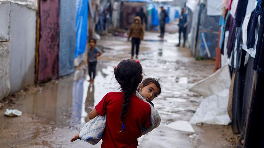 Orang-orang bergegas mengambil kantong tepung dari truk setelah militer Israel mulai mengevakuasi warga sipil Palestina menjelang ancaman serangan di Rafah, di tengah konflik yang sedang berlangsung antara Israel dan Hamas, di Rafah, di selatan Jalur Gaza 6 Mei 2024. (REUTERS/Hatem Khaled)