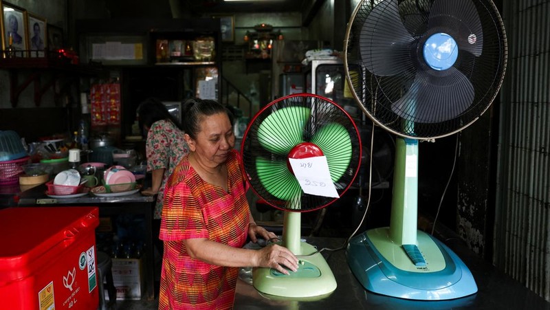 Orang-orang berjalan dengan payung melewati percikan air ketika pihak berwenang Thailand mengatakan bahwa orang-orang meninggal karena serangan panas tahun ini dan memperingatkan untuk menghindari aktivitas di luar ruangan, di Bangkok, Thailand, 5 Mei 2024. (REUTERS/Chalinee Thirasupa)
