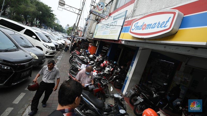 Aktivitas seorang warga menjaga kendaraan di salahsatu minimarket di kawasan Jakarta, Rabu (8/4/2024). (CNBC Indonesia/Tri Susilo)