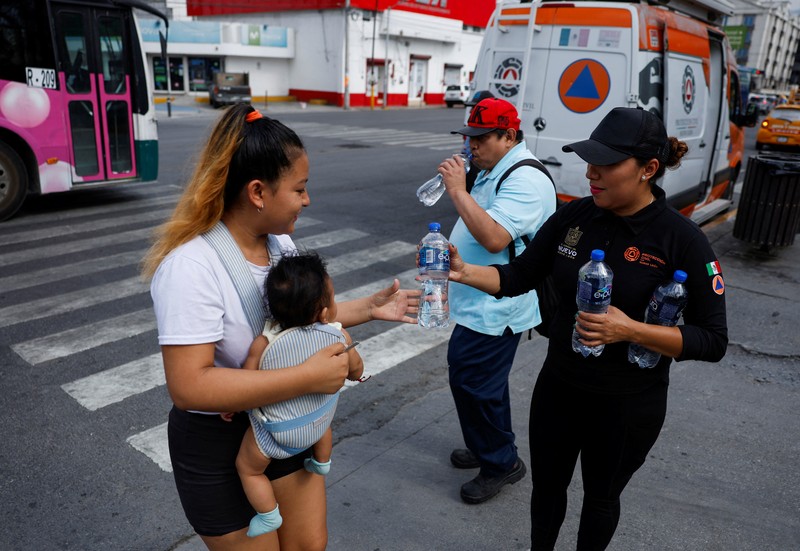 Orang-orang menutupi diri mereka dengan payung di samping orang lain saat mereka berjalan di trotoar saat suhu tinggi, di Mexico City, Meksiko 9 Mei 2024. (REUTERS/Henry Romero)
