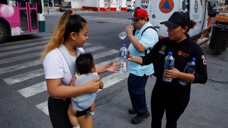 Orang-orang menutupi diri mereka dengan payung di samping orang lain saat mereka berjalan di trotoar saat suhu tinggi, di Mexico City, Meksiko 9 Mei 2024. (REUTERS/Henry Romero)