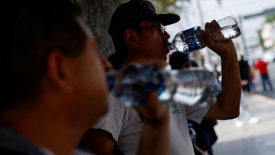 Orang-orang menutupi diri mereka dengan payung di samping orang lain saat mereka berjalan di trotoar saat suhu tinggi, di Mexico City, Meksiko 9 Mei 2024. (REUTERS/Henry Romero)