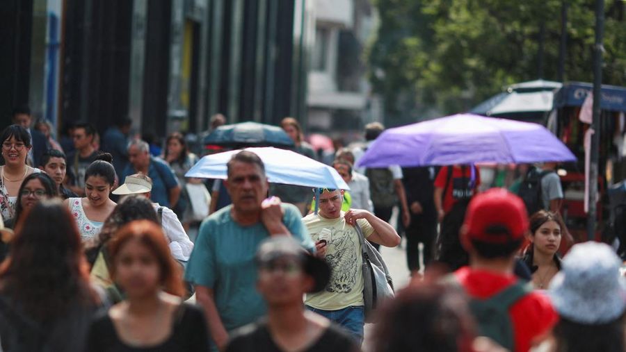 Orang-orang menutupi diri mereka dengan payung di samping orang lain saat mereka berjalan di trotoar saat suhu tinggi, di Mexico City, Meksiko 9 Mei 2024. (REUTERS/Henry Romero)