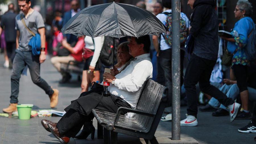 Orang-orang menutupi diri mereka dengan payung di samping orang lain saat mereka berjalan di trotoar saat suhu tinggi, di Mexico City, Meksiko 9 Mei 2024. (REUTERS/Henry Romero)