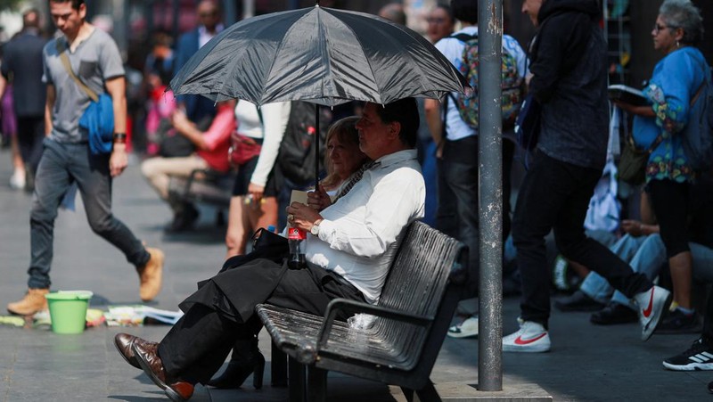 Orang-orang menutupi diri mereka dengan payung di samping orang lain saat mereka berjalan di trotoar saat suhu tinggi, di Mexico City, Meksiko 9 Mei 2024. (REUTERS/Henry Romero)