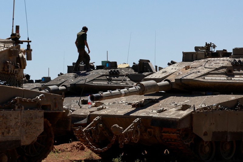 Tentara Israel berjalan di tengah kendaraan militer, di tengah konflik yang sedang berlangsung antara Israel dan kelompok Islam Palestina Hamas, dekat Perbatasan Israel-Gaza, di Israel selatan, 9 Mei 2024. (REUTERS/Amir Cohen)