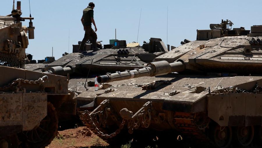 Seorang tentara Israel berjalan dengan kendaraan militer di dekat perbatasan Israel-Gaza, di tengah konflik yang sedang berlangsung antara Israel dan kelompok Islam Palestina Hamas, di Israel selatan, 8 Mei 2024. (REUTERS/Ammar Awad)