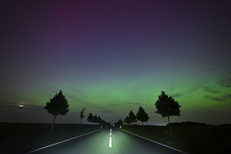 In this image taken with a long exposure, cars pass by as people look at the night sky towards the northern lights, or Aurora Borealis, on Friday, May 10, 2024, in Estacada, Ore. The National Oceanic and Atmospheric Administration issued a rare severe geomagnetic storm warning when a solar outburst reached Earth on Friday afternoon, hours sooner than anticipated. The effects were due to last through the weekend and possibly into next week. (AP Photo/Jenny Kane)